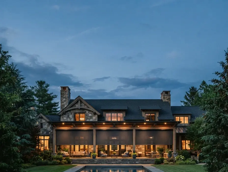 Tighter view of a luxury home with charcoal exterior motorized shades filling the covered loggia, lawn and pool edge in foreground